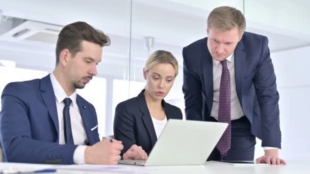 Equipo profesional serio discutiendo y trabajando en el ordenador portátil — Vídeos de Stock