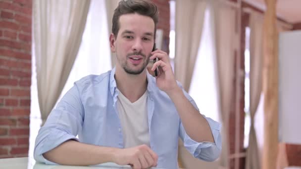 Веселый молодой человек разговаривает по смартфону — стоковое видео