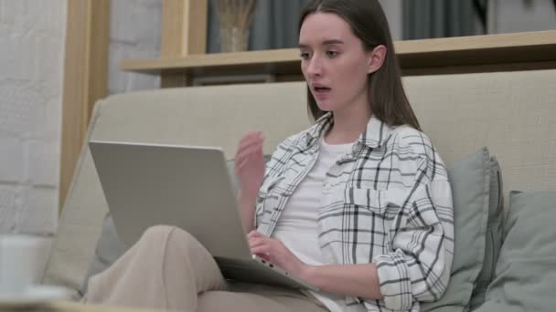 Jonge vrouw reageert op mislukking op laptop op sofa — Stockvideo