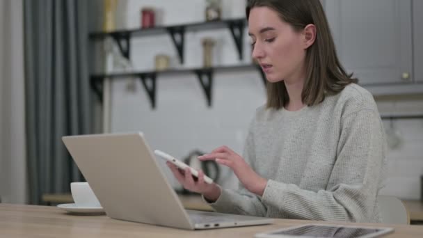 Junge Frau spricht im Wohnzimmer mit Smartphone — Stockvideo