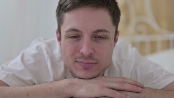 Detailní záběr mladého muže usmívajícího se na kameru v posteli — Stock video