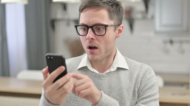 Hombre joven reaccionando a la pérdida en el Smartphone — Vídeo de stock