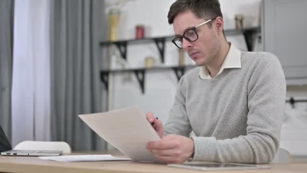 Молодой человек работает над документами, бумажной работой — стоковое видео
