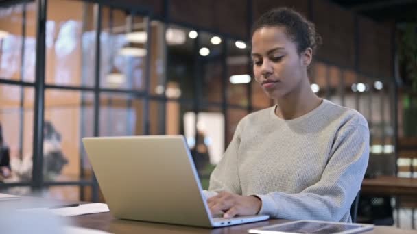 Afrikaanse vrouw glimlachen in de richting van de camera tijdens het werken op laptop — Stockvideo