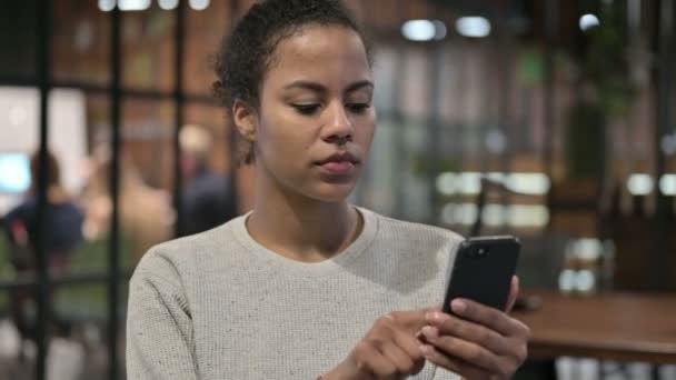 Mujer africana molesta reaccionando a la pérdida en el teléfono — Vídeo de stock