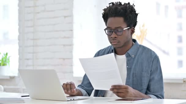 Verontruste jonge Afrikaanse man werkt aan document — Stockvideo