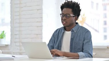 Dizüstü bilgisayarında diş ağrısı olan genç bir Afrikalı.