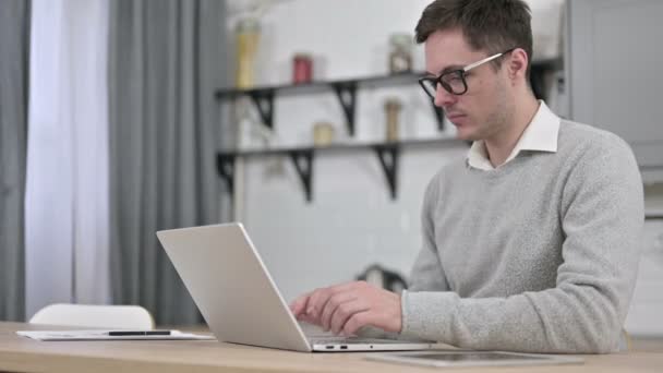 Jeune homme travaillant sur ordinateur portable à la maison — Video