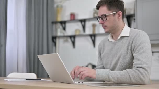 Zieke jonge man hoesten tijdens het werken op laptop — Stockvideo