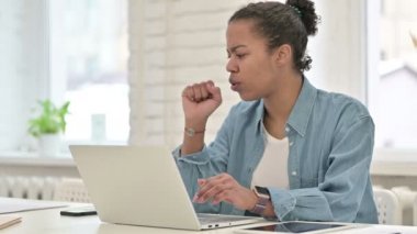 Öksürük hastası genç Afrikalı kadın dizüstü bilgisayarda çalışıyor, boğazı ağrıyor.