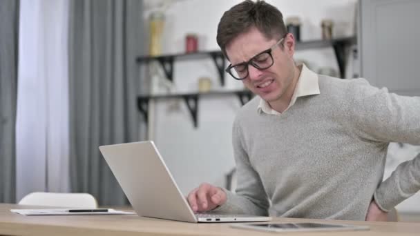 Junger Mann mit Rückenschmerzen arbeitet am Laptop — Stockvideo