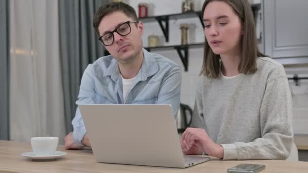 Серьезная молодая пара, работающая над ноутбуком в гостиной — стоковое видео