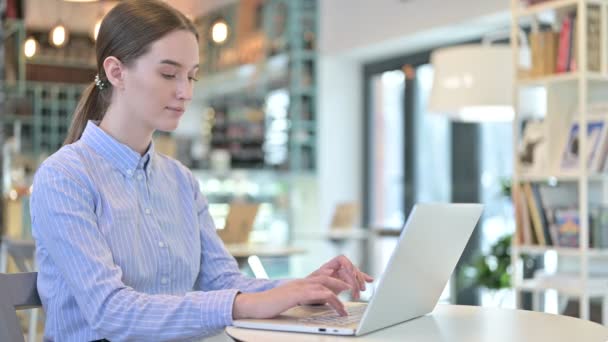Использование ноутбука молодым предпринимателем улыбаясь перед камерой в кафе — стоковое видео