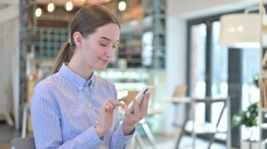 Kafede akıllı telefon kullanan genç bir iş kadını.