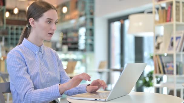 Молодая предпринимательница празднует на ноутбуке в кафе — стоковое видео