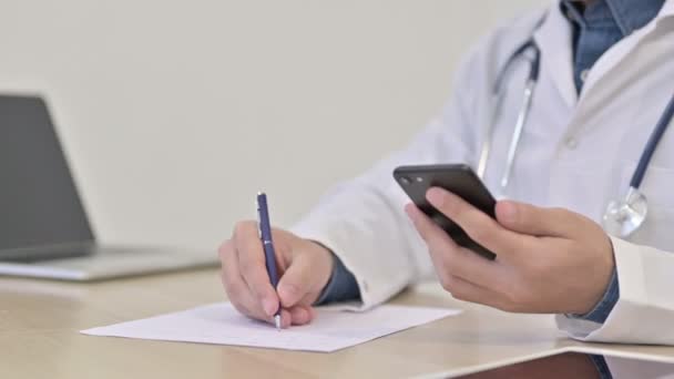 Doctor usando Smartphone Escribir en papel Primer plano — Vídeo de stock