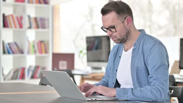 Junger Mann mit Brille arbeitet am Laptop — Stockvideo