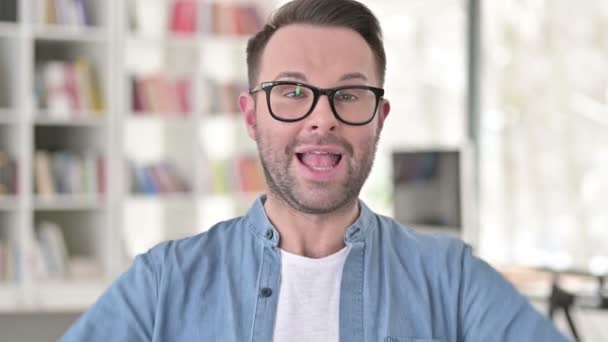 Возбужденный молодой человек в очках празднует успех — стоковое видео