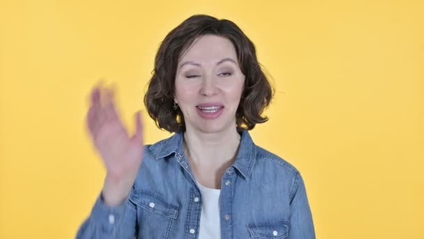 Old Woman Waving at the Camera in Yellow Background — Wideo stockowe