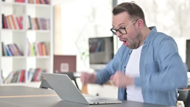 Jovem de óculos comemorando o sucesso no laptop — Vídeo de Stock