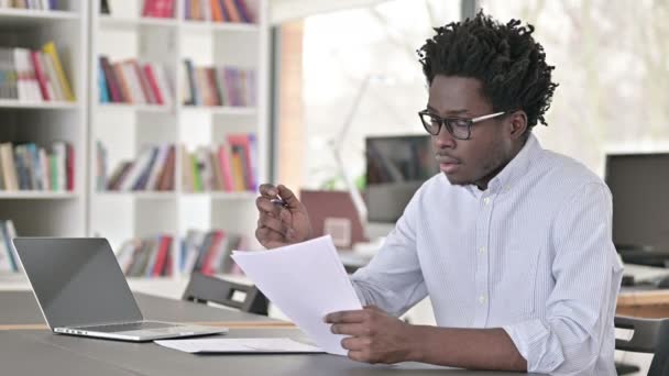 Африканский человек, занимающийся бумажной работой в офисе — стоковое видео