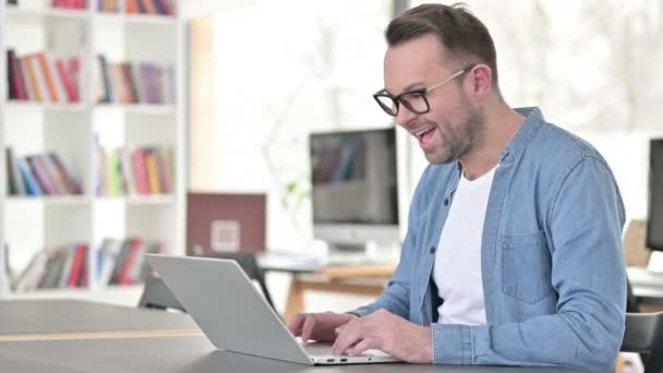 Chat de vídeo on-line no laptop por Jovem em óculos — Vídeo de Stock