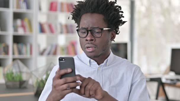 Молодой африканский человек теряет на смартфоне — стоковое видео