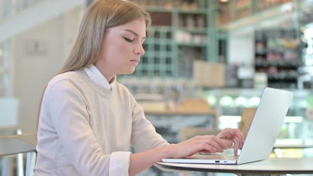Молода жінка з головним болем за допомогою ноутбука в кафе. — стокове відео