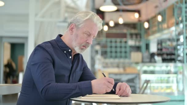 Vieil homme réfléchi faisant de la paperasserie dans Cafe — Video