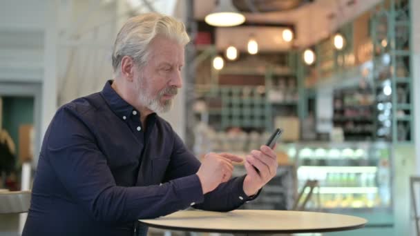 Использование смартфона Focused Old Man в кафе — стоковое видео