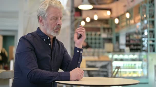 Wütender alter Mann spricht im Café auf Smartphone — Stockvideo