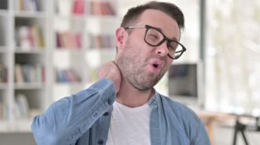 Gözlüklü genç adam boyun ağrısı çekiyor.