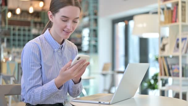 Ung affärskvinna använder Smartphone med laptop i Cafe — Stockvideo