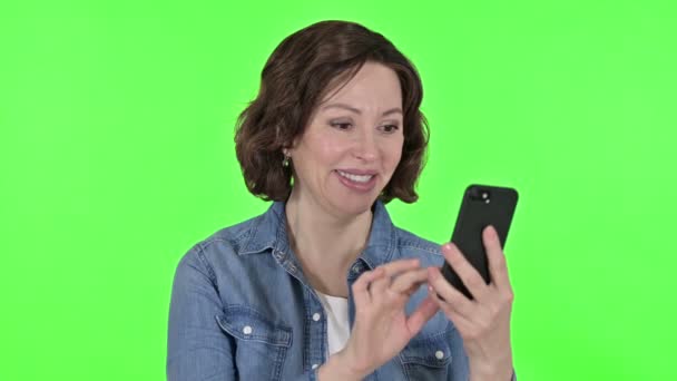 緑のクロマキーの背景にスマートフォンを使用している老婦人 — ストック動画