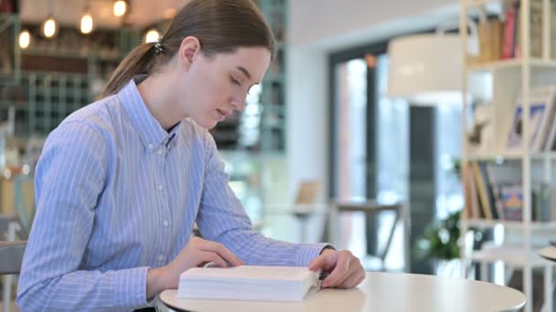 Joven Empresaria Enfocada Leyendo Libro en Café — Vídeos de Stock