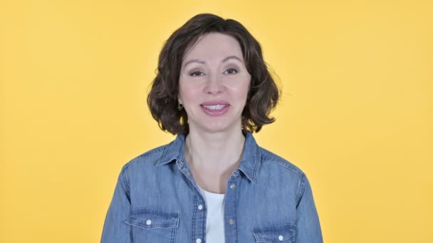Gammal kvinna ler mot kameran, gul bakgrund — Stockvideo