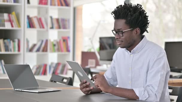 Απασχολημένος αφρικανικός άνθρωπος που χρησιμοποιεί ψηφιακή ταμπλέτα στην εργασία — Αρχείο Βίντεο