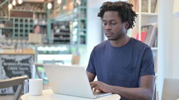 Hombre africano con ordenador portátil mirando a la cámara en Café — Vídeos de Stock