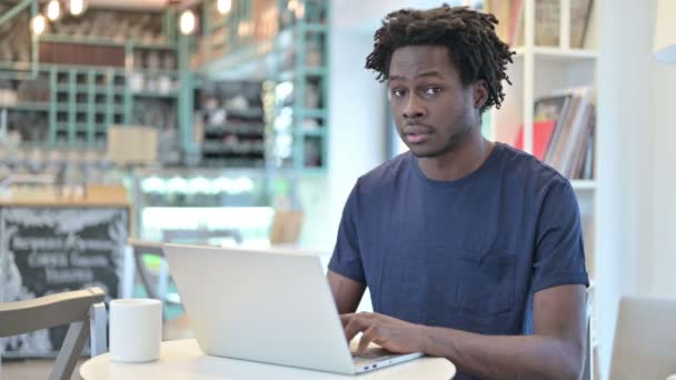Pollici giù da uomo africano con il computer portatile in Cafe — Video Stock