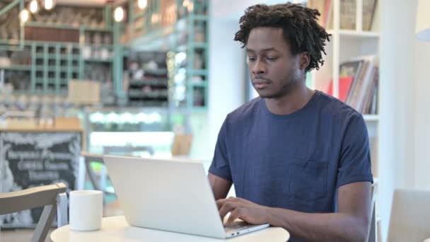 Uomo africano con computer portatile sorridente alla macchina fotografica in Cafe — Video Stock