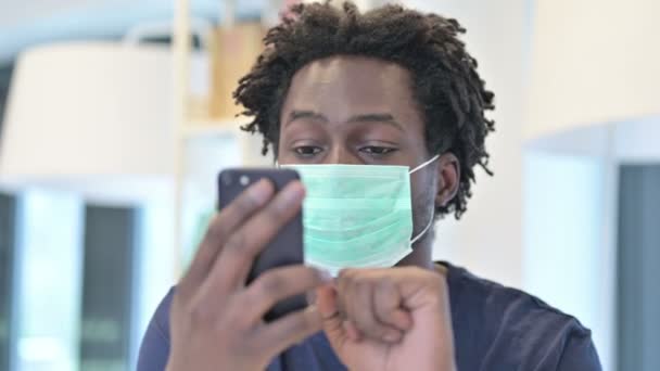 Afrikansk man med ansiktsmask Använda smartphone — Stockvideo
