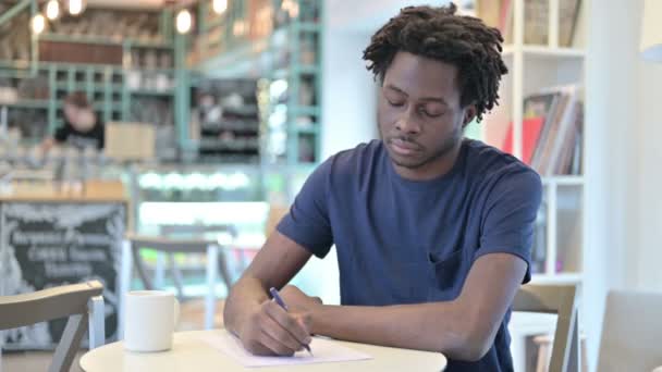 Homem Africano atencioso fazendo papelada no café — Vídeo de Stock