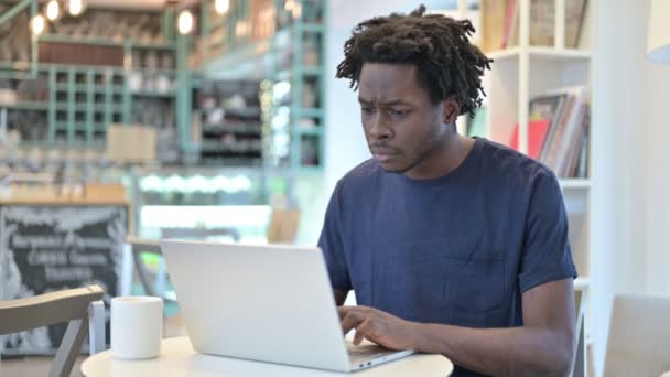 Schockierter Afrikaner arbeitet in Café am Laptop — Stockvideo