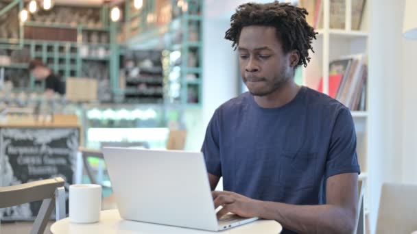 Uomo africano pensieroso che lavora sul computer portatile in Cafe — Video Stock