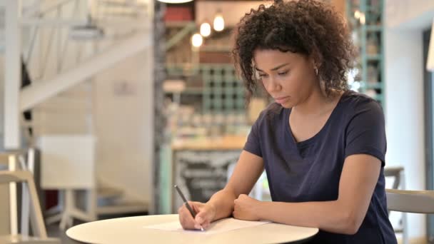 Thoughtful Young African Woman doing Paperwork in Cafe — Stock Video