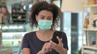 Yüzü Maskeli Genç Afrikalı Kadın 'ın Akıllı Telefon Kullanımı Portresi 