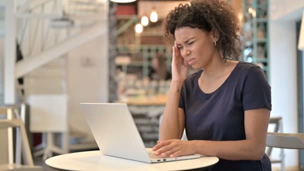 Giovane donna africana con mal di testa utilizzando il computer portatile in Cafe — Video Stock