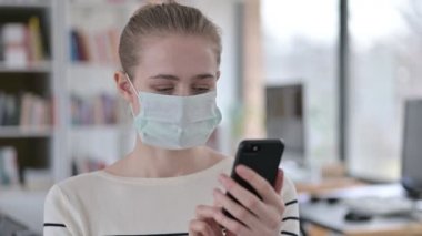 Akıllı telefon kullanan Yüz Maskeli Genç Kadın Portresi 