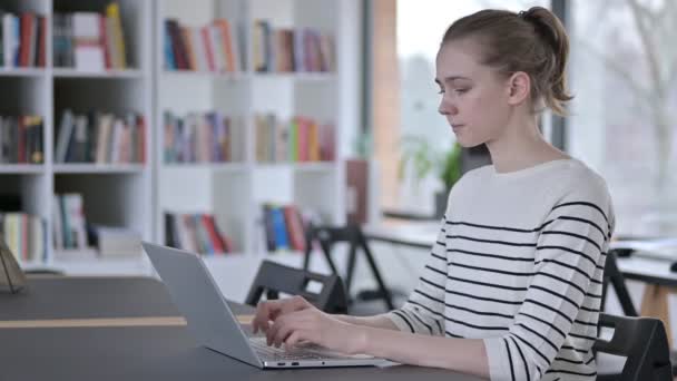 Utilisation de l'ordinateur portable par la jeune femme regardant la caméra dans la bibliothèque — Video