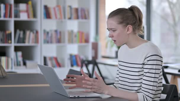 Расстроенная молодая женщина реагирует на потерю ноутбука в библиотеке — стоковое видео
